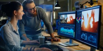 A team of editors working together on a corporate video at a computer deck with multiple monitors