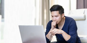 a man seriously focused on reading an article on his laptop