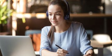 A women doing an online course on her laptop at the kitchen table
