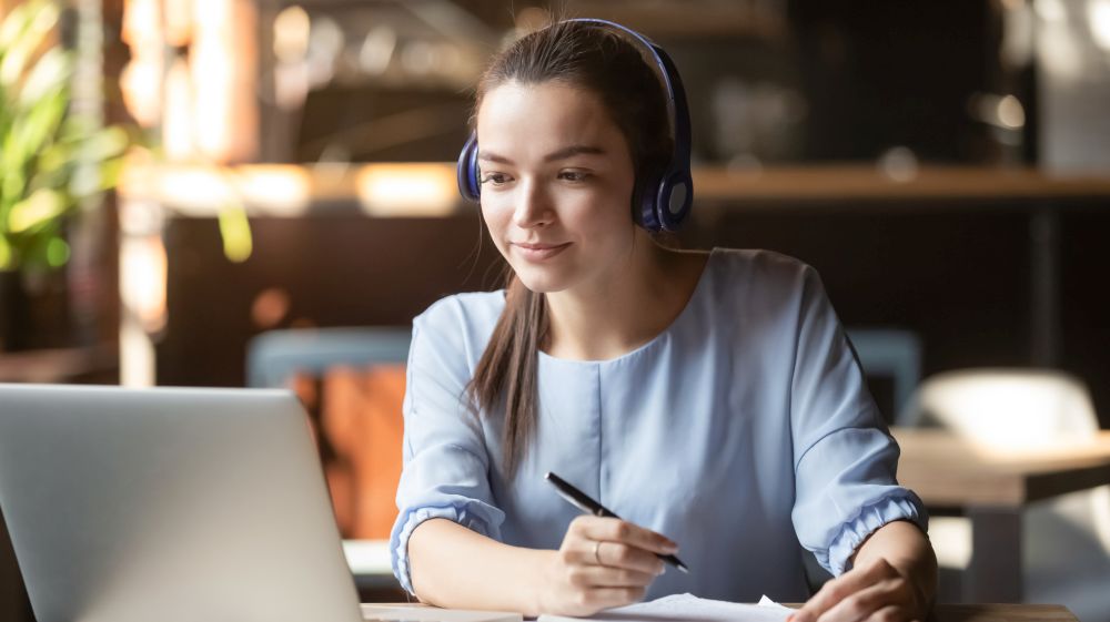 A women doing an online course on her laptop at the kitchen table