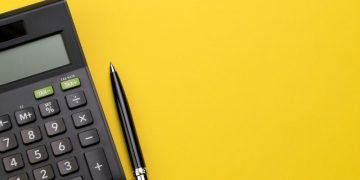 A calculator and pen on a sufrace symbolising do accounting and tax work