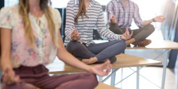 A group of healthy entrepreneurs meditating during the work day