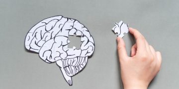 A diagram of a brain with a person holding a missing piece as a metaphor for repairing mental health