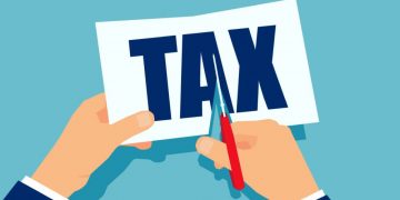 Hands cutting up paper with the word tax on, symbolising how EIS can lessen tax payable for investors