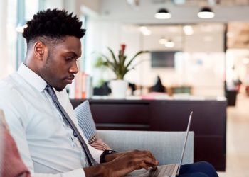 A person working on a couch with a laptop out of a co-working space due to his workplaces flexible working policy