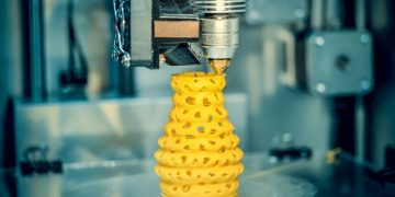 A 3d printer, printing a yellow vase