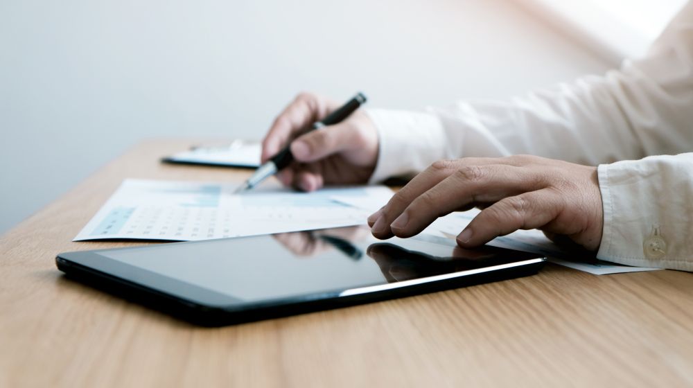 Business person writing e-learning about compliance on a tablet