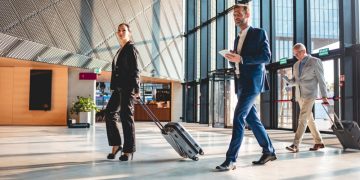 Business travellers walking through an airport with luggage