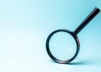 Magnifying glass against a blue background as a symbol for how thorough tax investigations are