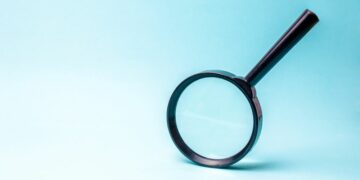 Magnifying glass against a blue background as a symbol for how thorough tax investigations are