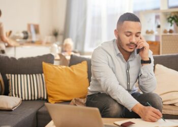 Employee working from a living table at home with family in the background