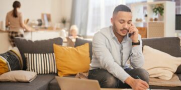 Employee working from a living table at home with family in the background