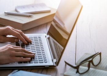 A person using a laptop to write down the next company blog