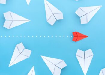 A paper airplane cutting through a range of disorientated planes symbolising how businesses can stand out and beat their local competitors