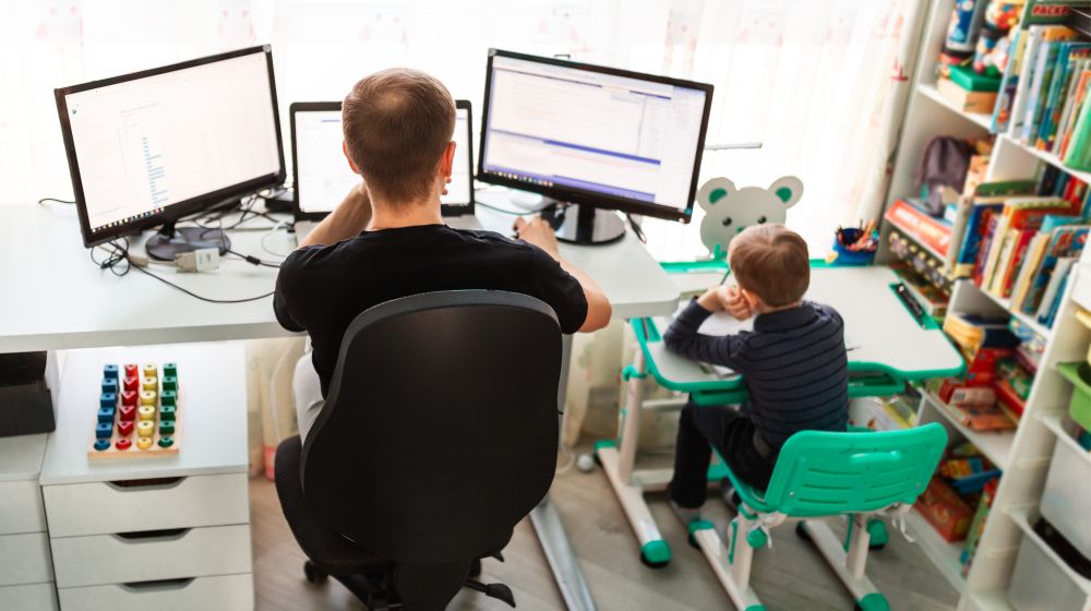 A new entrepreneur working from home alongside his child to minimise cost