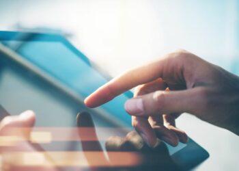 Persons hand touching the display, presented as a tablet, of a digital sign used to attract new customers.