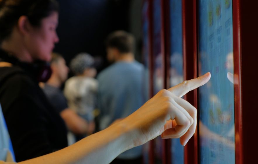 A woman's hand reaching to touch the display of a digital sign at a store.