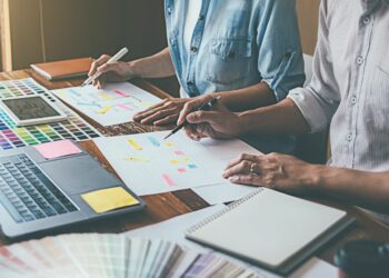 Two people making a website branding strategy by scooping colours and designs on the laptop in front of them.