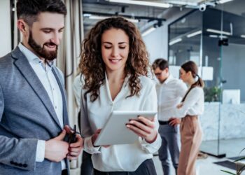A woman and a man looking at a presentation on a tablet representing two bankers.