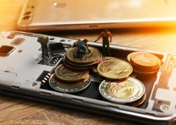 An illustration of cashless society in the making by workers placing coins into a phone.