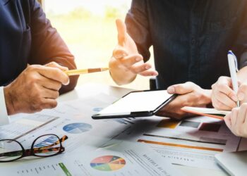 People on a meeting working on a strategy to improve retail sales looking at their tablet and papers.