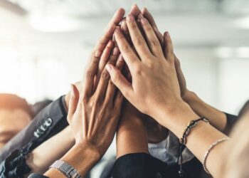 A team of people high fiving as a creative winning team.