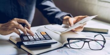 A person using a calculator at their desk to calculate personal taxes