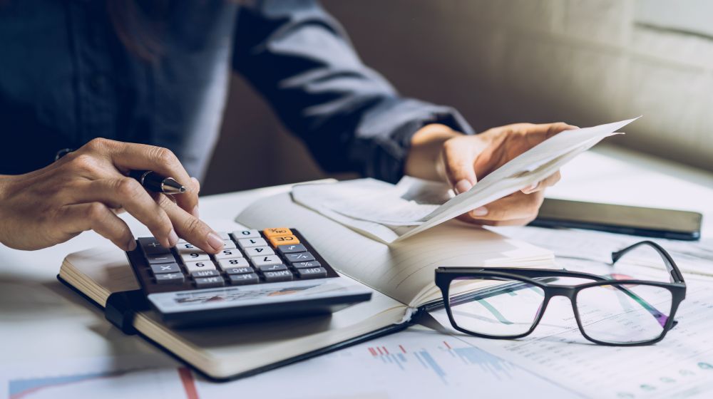 A person using a calculator at their desk to calculate personal taxes