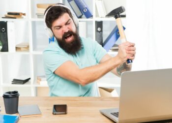 A person smashing their laptop with a hammer as an ironic example of how to fix your slow internet