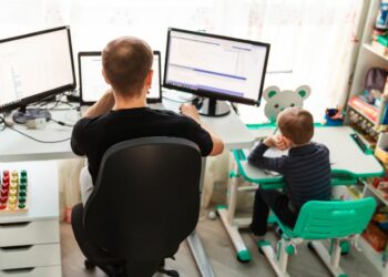 A father working from home with his son sitting next to him