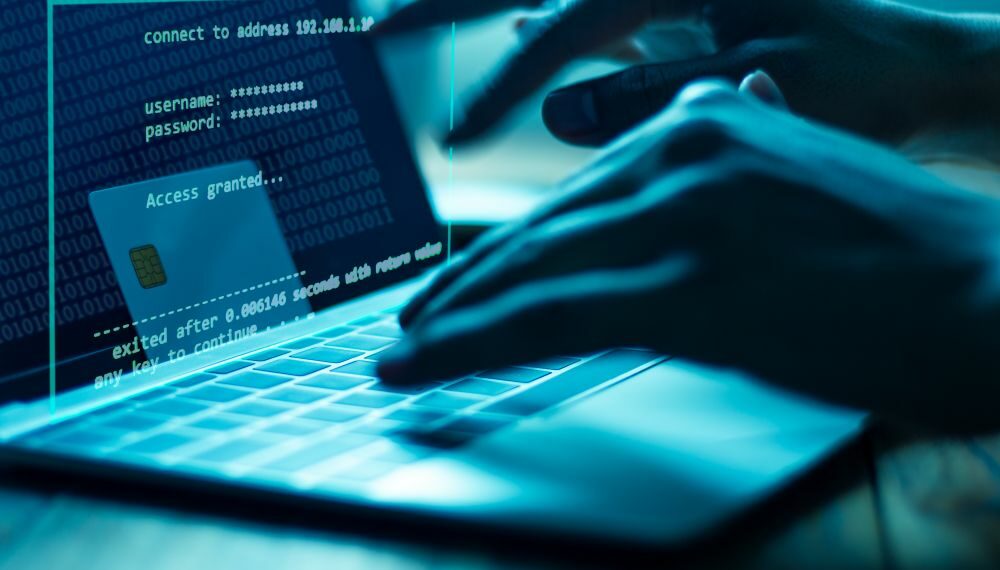 A hacker using a laptop to steal payment details and commit fraud