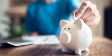 A man putting money in a piggybank, saving to make an equity investment