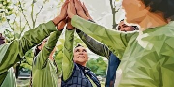 A team of employees, group high fiving each other, as an example of team bonding on a corporate retreat