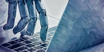 A robot hand typing on a laptop