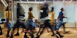 A busy office where employees are blurred as they rush through the office