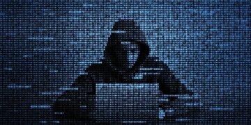 A hacker in code form working at a laptop to create ransomware