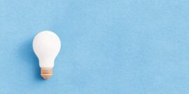 A blue background with a single lightbulb lit up on the left, as an example for a great idea coming from nothing