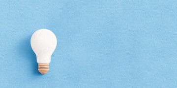 A blue background with a single lightbulb lit up on the left, as an example for a great idea coming from nothing