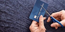 A persons hands close-up cutting a credit or debit card with scissors